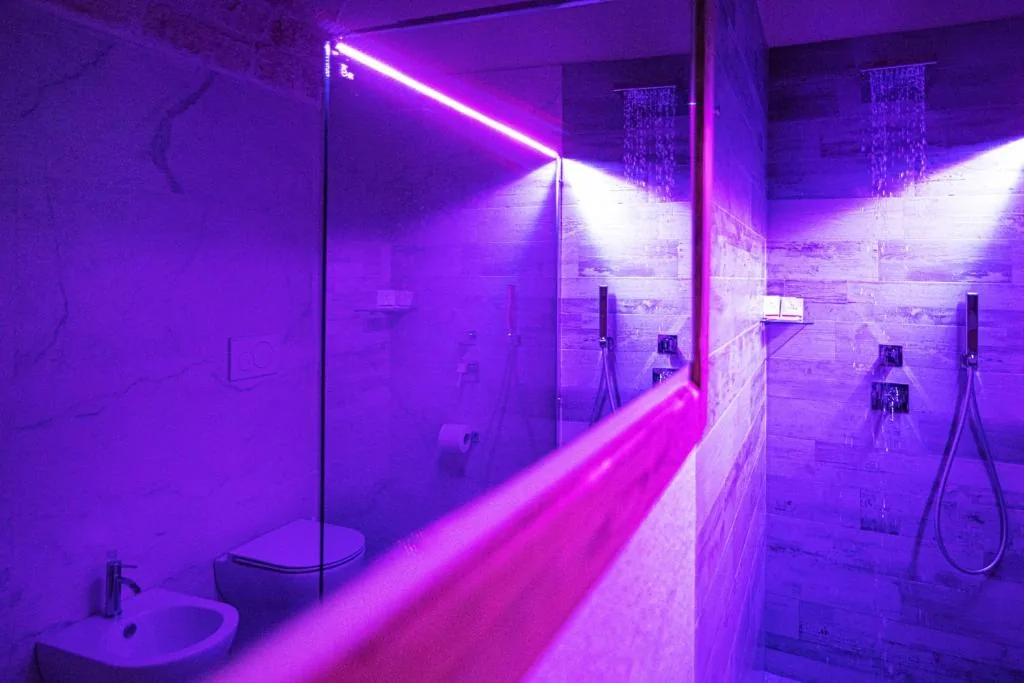 Bathroom with dual rain showers under violet mood lighting