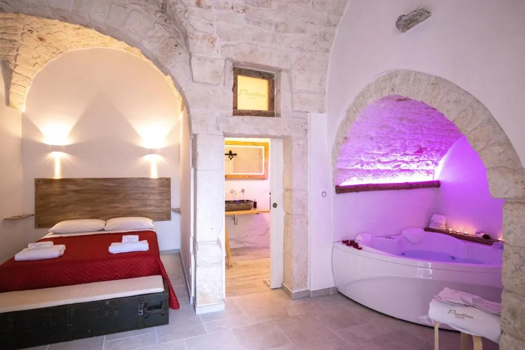 Pasithèa Suite — star-vaulted stone room with bed and heart-shaped whirlpool in warm light