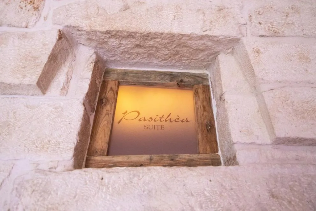 Backlit Pasithèa Suite sign set into a stone wall