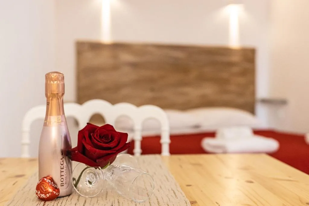 Welcome of a single rose, sparkling wine and a chocolate on a wooden table